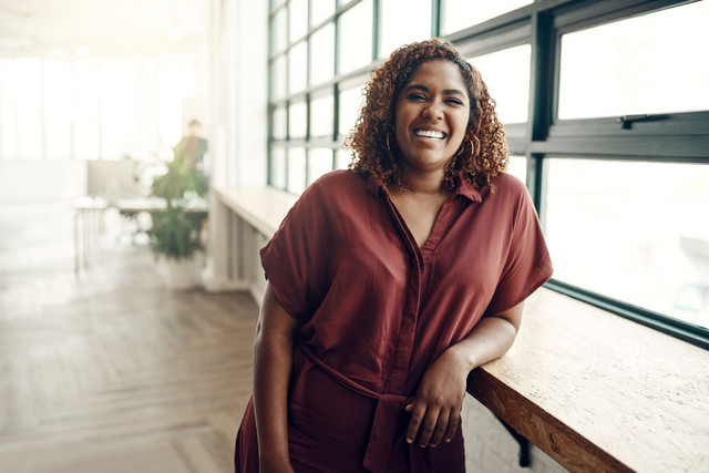 femme noire appuyée bureau fenetre
